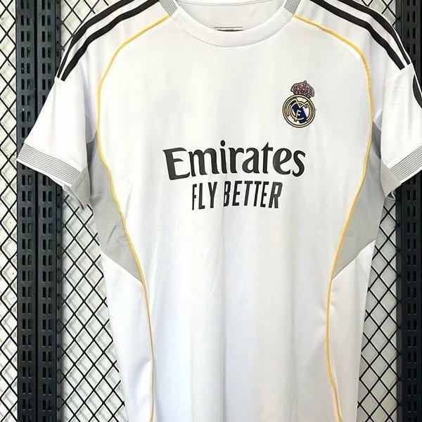 Real Madrid white short-sleeve soccer jersey with black shoulder stripes, yellow side panels, and front sponsor text