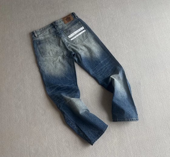 Straight-Leg Jeans. Those who don't chase trends set the trends. Straight-leg, uncompromising. MOMOTARO JEANS — Make friends with time. This fabric comes from Kojima by the Seto Inland Sea, the holy land of Japanese denim, where craftsmen still weave with vintage shuttle looms, thread by thread, using Zimbabwean cotton...