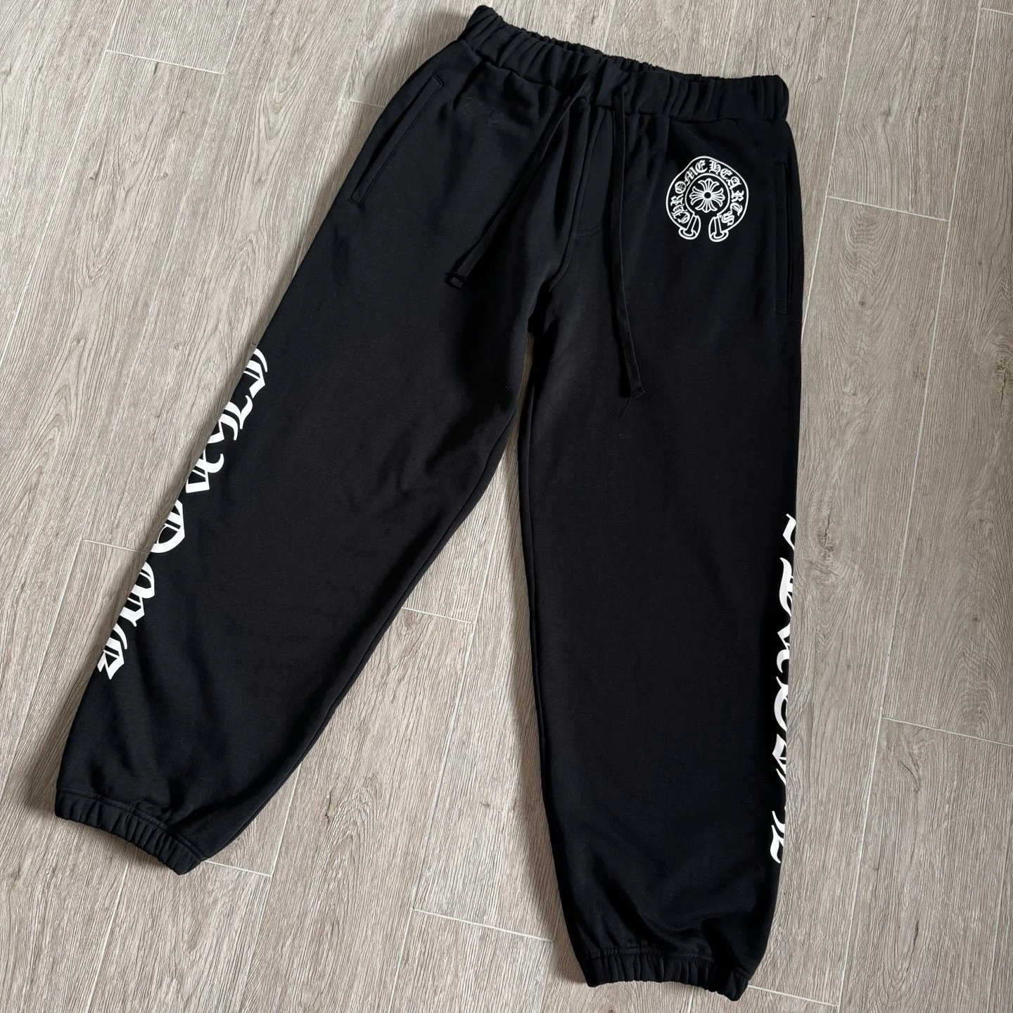 Black and white sweatpants with blue Sanskrit letters on the side
