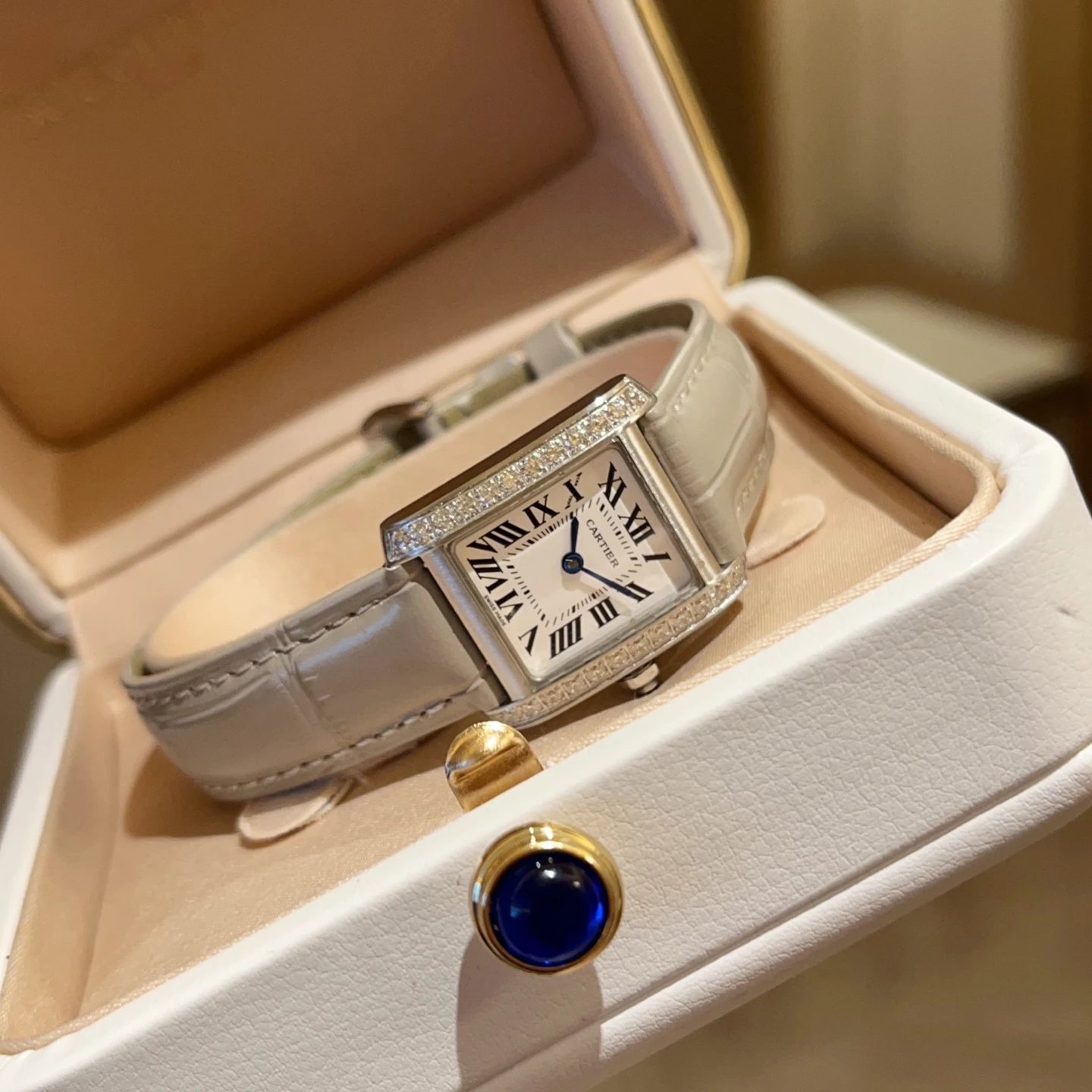 Cartier horloge met rechthoekige wijzerplaat, met edelstenen bezette lunette en grijze leren band