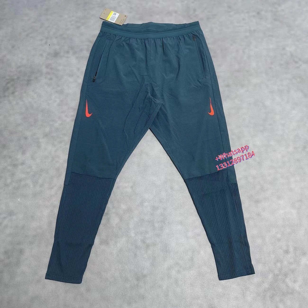 Nike Jackets Trail hooded zip-up windbreaker — Blue sports pants with double orange hook-and-loop closures and a ribbed texture